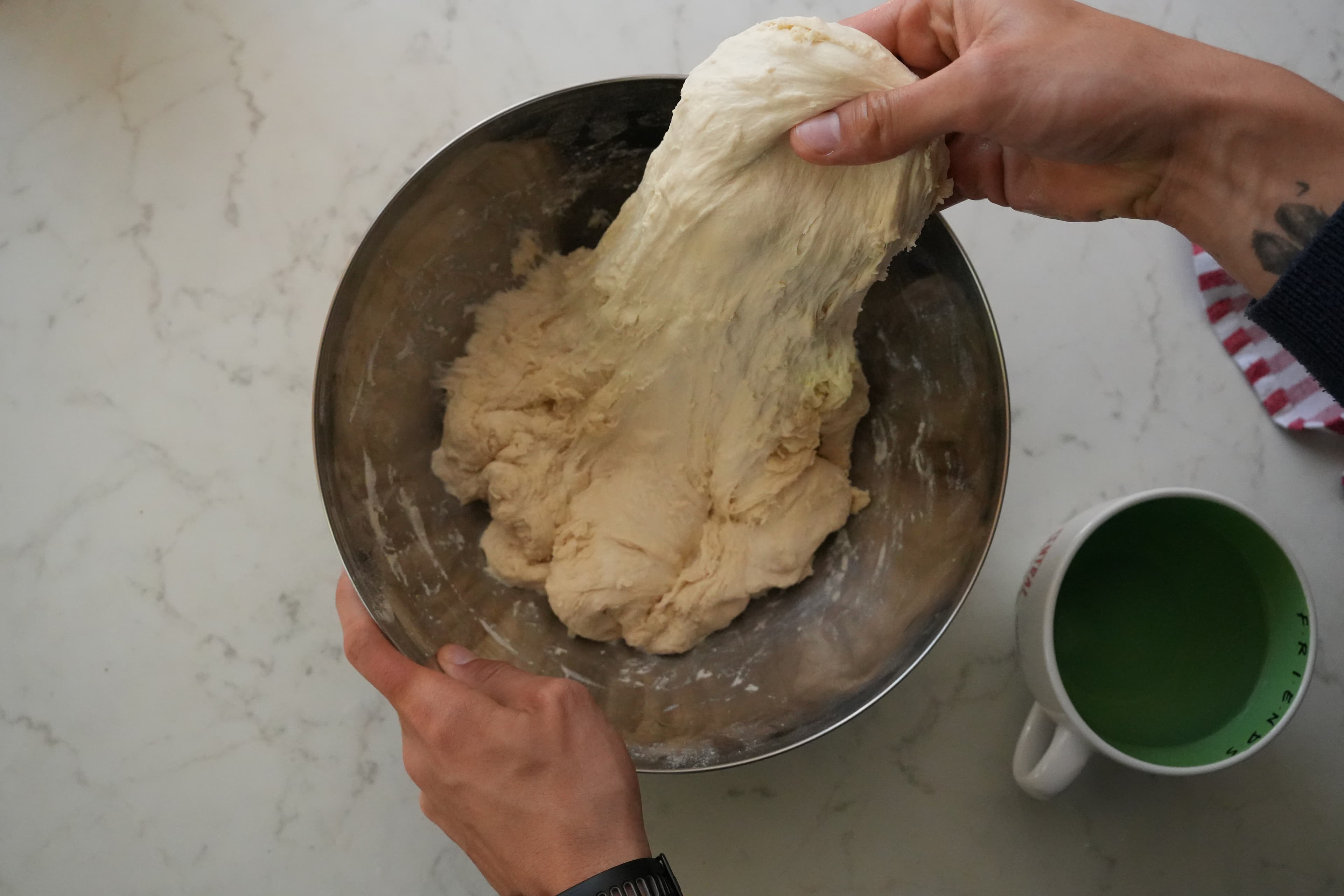 First stretch and fold, showing hand placement under the dough.